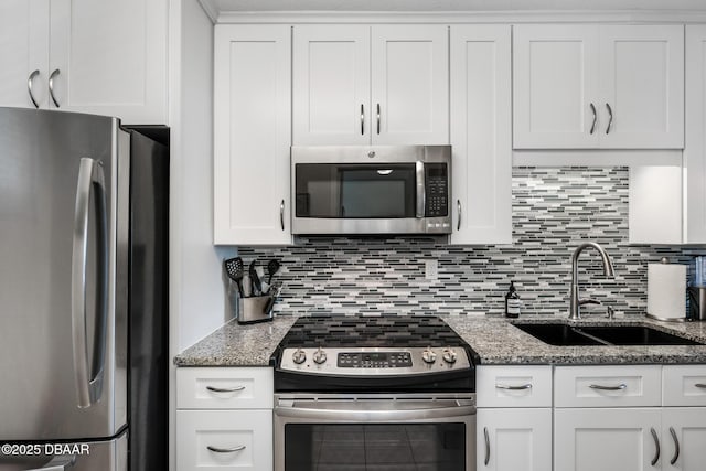 kitchen featuring white cabinets, appliances with stainless steel finishes, decorative backsplash, and a sink