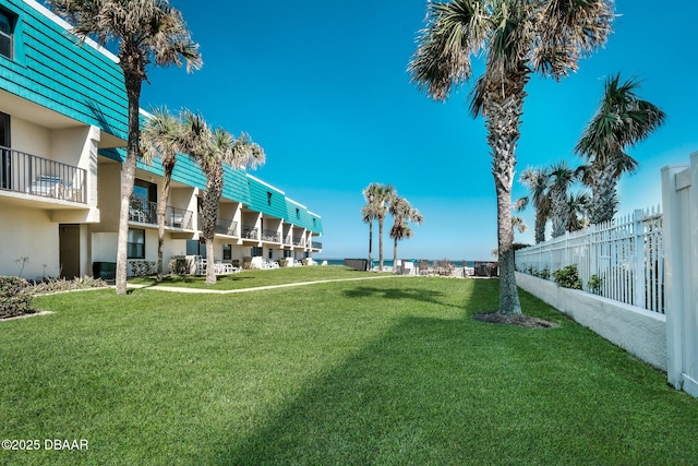 view of community featuring a lawn and fence