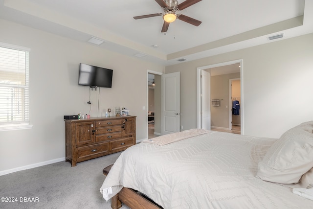 bedroom featuring a tray ceiling, light colored carpet, and ceiling fan