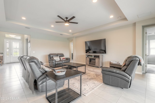 living room with light tile patterned flooring, a tray ceiling, french doors, and ceiling fan