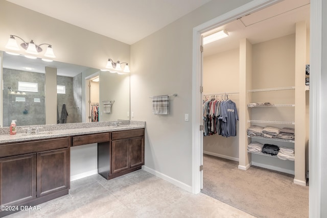 bathroom with tile patterned flooring, vanity, and a tile shower