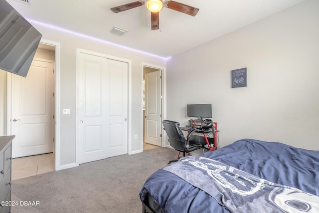 bedroom featuring light carpet, ceiling fan, and a closet