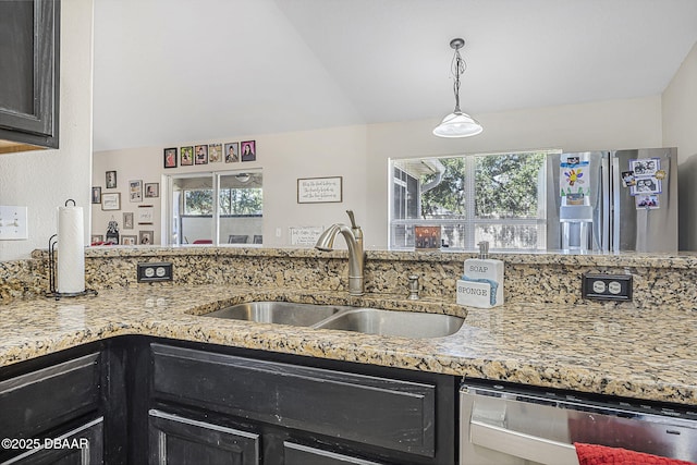 kitchen with sink, light stone countertops, hanging light fixtures, and appliances with stainless steel finishes