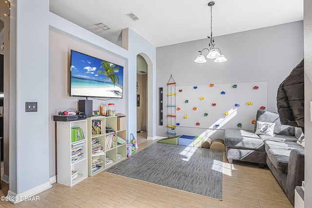 rec room featuring a notable chandelier and light wood-type flooring