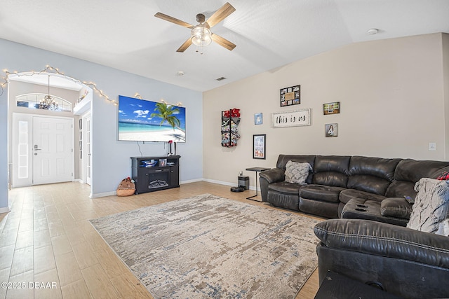 living room featuring hardwood / wood-style flooring, lofted ceiling, and ceiling fan with notable chandelier