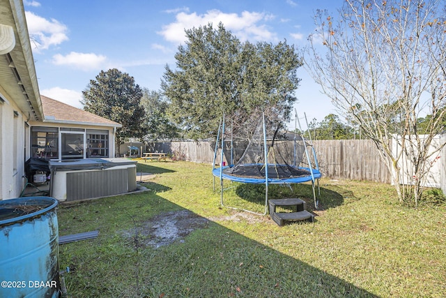 view of yard with a trampoline, central AC, a hot tub, and a sunroom