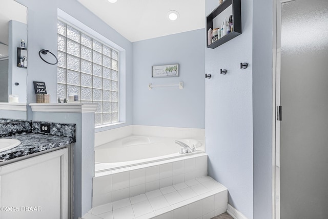 bathroom with vanity, a relaxing tiled tub, and a wealth of natural light