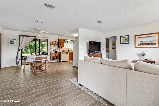 living room with a textured ceiling, hardwood / wood-style flooring, and ceiling fan