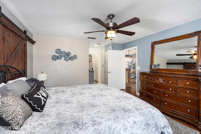 840 River Oak Dr W, Ormond Beach, FL 32174 - bedroom with a barn door, a textured ceiling, ceiling fan, and dark wood-style flooring