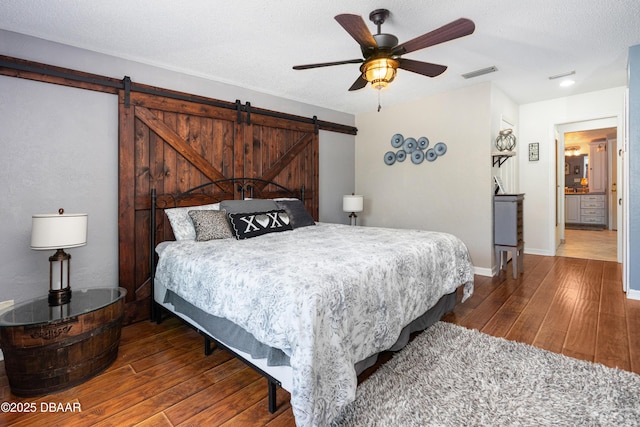 840 River Oak Dr W, Ormond Beach, FL 32174 - bedroom with a barn door, hardwood / wood-style floors, ceiling fan, and a textured ceiling