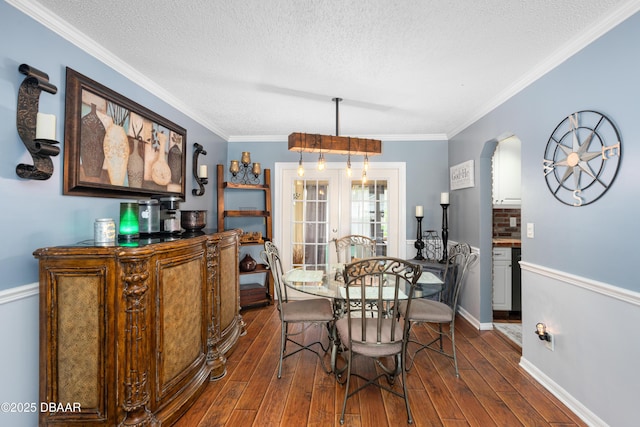 840 River Oak Dr W, Ormond Beach, FL 32174 - dining room with dark wood-style flooring, a textured ceiling, arched walkways, ornamental molding, and a dry bar