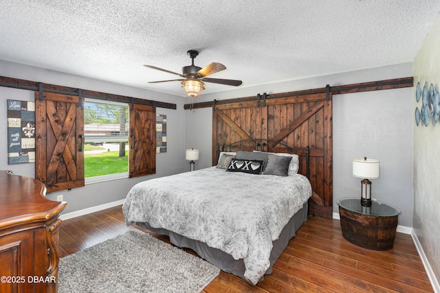 840 River Oak Dr W, Ormond Beach, FL 32174 - bedroom with a barn door, wood finished floors, a textured ceiling, and a ceiling fan