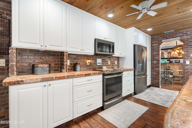 840 River Oak Dr W, Ormond Beach, FL 32174 - kitchen with stainless steel appliances, wood ceiling, brick wall, ceiling fan, and dark wood-style flooring