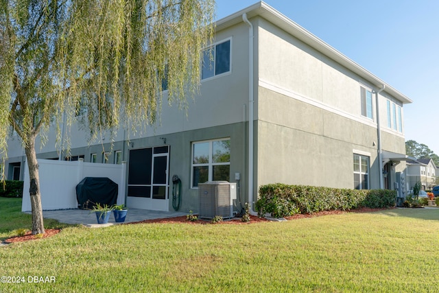 back of property featuring central AC unit and a lawn