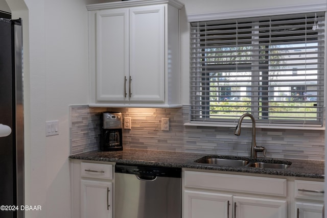 kitchen featuring dark stone countertops, sink, white cabinets, and stainless steel dishwasher