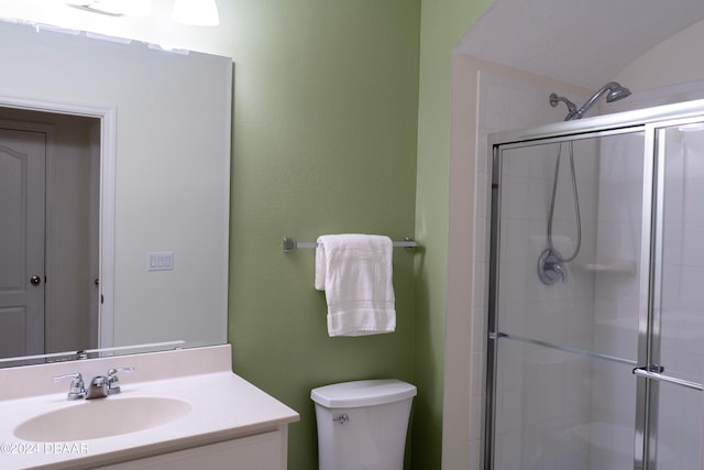 bathroom with vanity, toilet, a shower with door, and vaulted ceiling