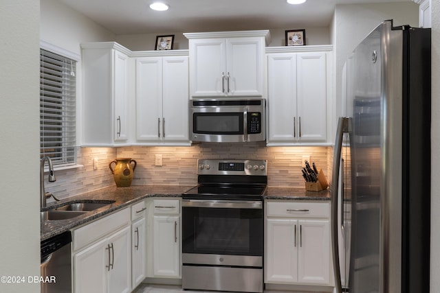 kitchen with backsplash, stainless steel appliances, white cabinetry, and sink