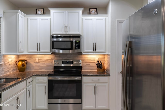 kitchen featuring backsplash, white cabinetry, dark stone counters, and appliances with stainless steel finishes