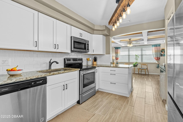 kitchen featuring beamed ceiling, appliances with stainless steel finishes, white cabinetry, and sink