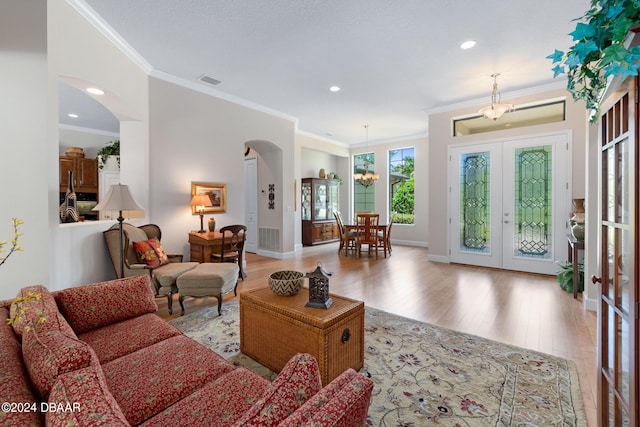 living room with french doors, crown molding, and a chandelier