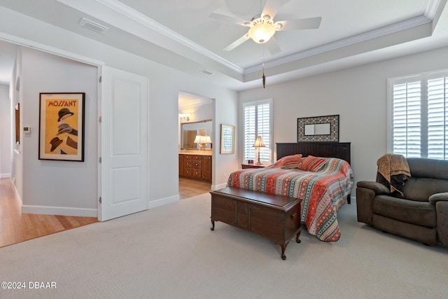 carpeted bedroom featuring ceiling fan, ensuite bathroom, ornamental molding, and a tray ceiling