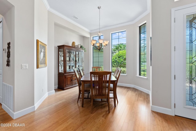 dining room with an inviting chandelier, crown molding, and light hardwood / wood-style flooring