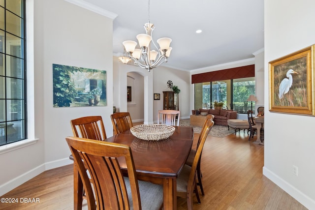 dining space with ornamental molding, light hardwood / wood-style flooring, a chandelier, and plenty of natural light