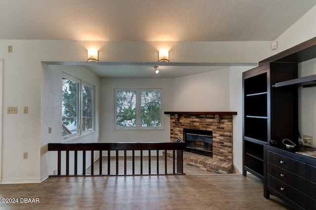 living room with a fireplace, a textured ceiling, and hardwood / wood-style flooring