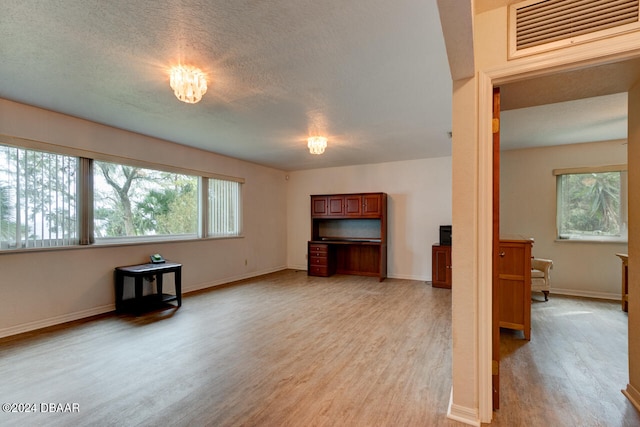 unfurnished living room featuring light hardwood / wood-style floors and a textured ceiling