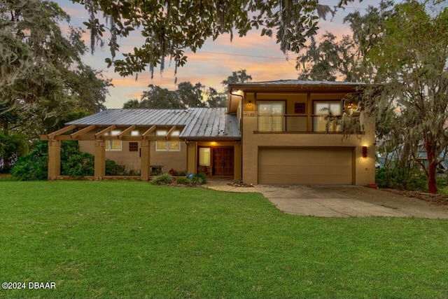 view of front of property with a balcony, a garage, and a lawn