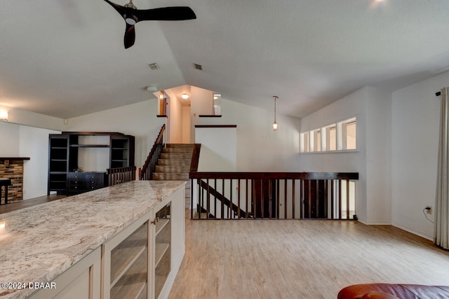 kitchen with ceiling fan, wine cooler, light stone counters, lofted ceiling, and light wood-type flooring