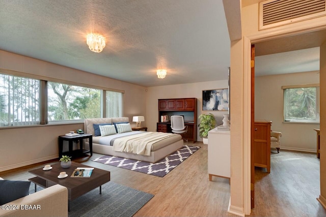 bedroom with light hardwood / wood-style floors and a textured ceiling