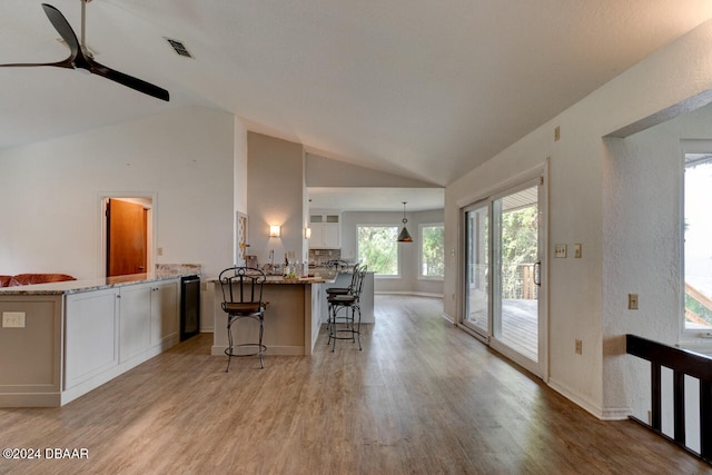 kitchen with a kitchen breakfast bar, decorative light fixtures, lofted ceiling, white cabinets, and light wood-type flooring