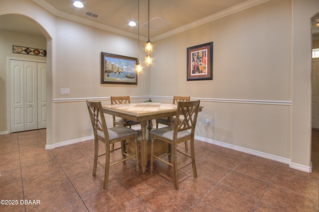 dining space featuring ornamental molding and dark tile patterned flooring