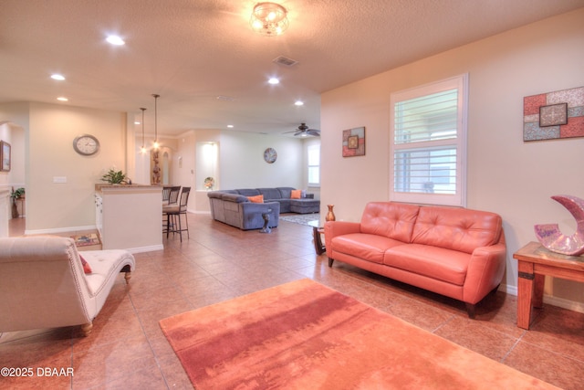 living room with a textured ceiling, ceiling fan, and light tile patterned floors