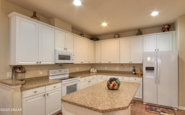 kitchen with white appliances, a center island, and white cabinetry