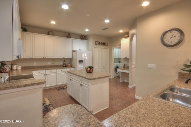 kitchen featuring sink, white cabinets, washer / clothes dryer, a kitchen island, and white refrigerator with ice dispenser