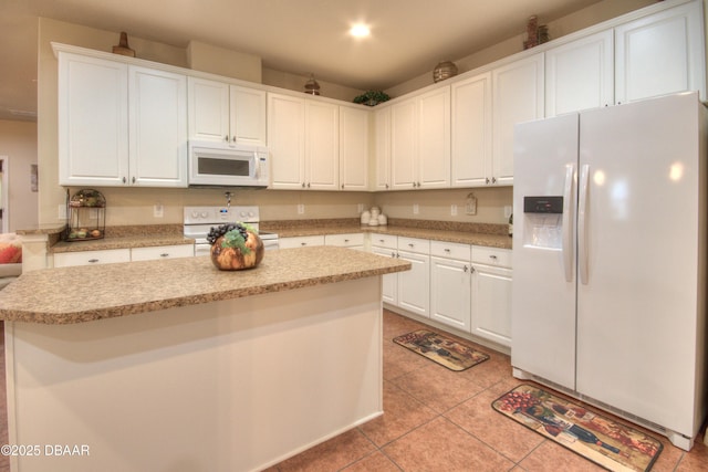 kitchen with white appliances, a center island, white cabinets, and light tile patterned flooring