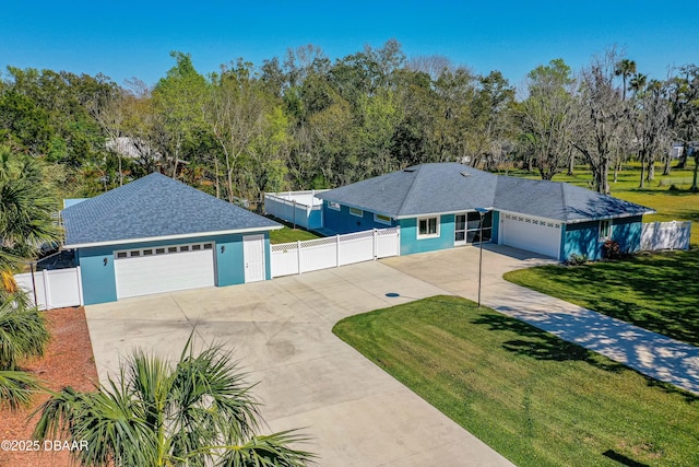 ranch-style house featuring driveway, an attached garage, fence, a front lawn, and stucco siding