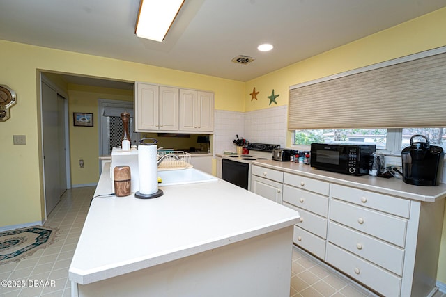 kitchen featuring black microwave, electric range, visible vents, white cabinetry, and a sink