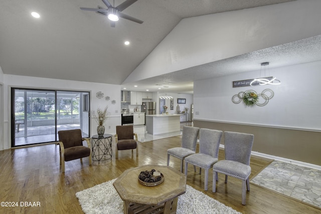 living room with a textured ceiling, high vaulted ceiling, light hardwood / wood-style flooring, and ceiling fan