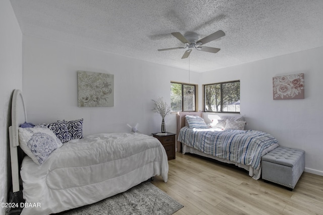 bedroom with ceiling fan, light hardwood / wood-style floors, and a textured ceiling