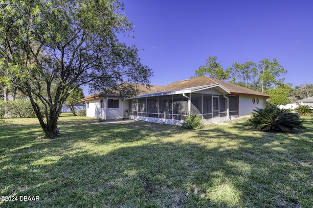 rear view of house featuring a lawn and a sunroom