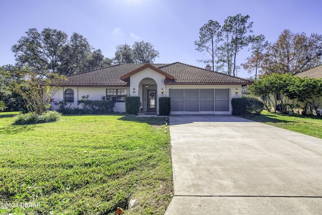 mediterranean / spanish-style home with a garage and a front lawn