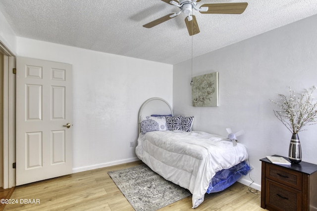 bedroom with ceiling fan, light hardwood / wood-style floors, and a textured ceiling