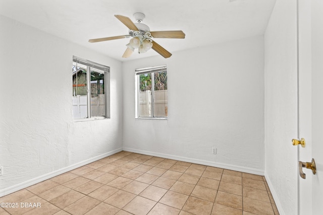 unfurnished room featuring ceiling fan, a textured wall, and baseboards