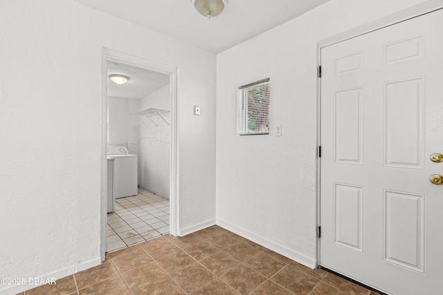 hallway featuring washer / clothes dryer, tile patterned floors, and baseboards