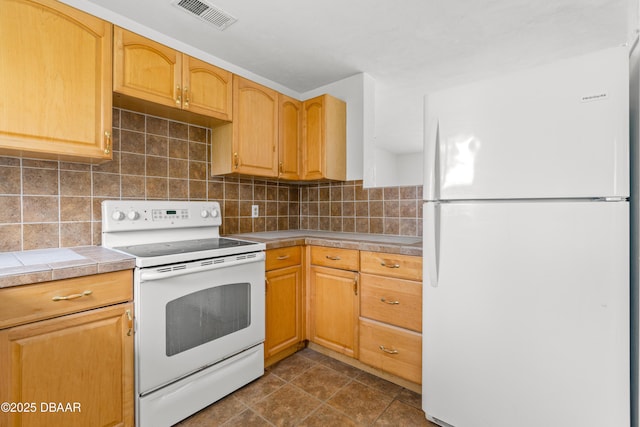 kitchen with tile countertops, white appliances, visible vents, and tasteful backsplash