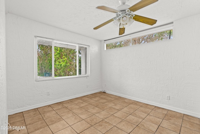 unfurnished room with a wealth of natural light, a textured wall, and baseboards