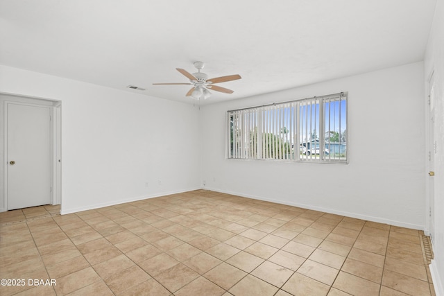 spare room featuring ceiling fan, visible vents, and baseboards